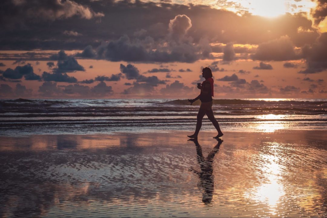person walking on beach at sunset
