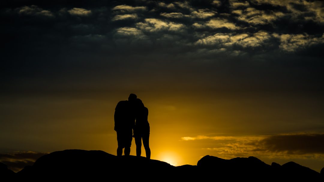 Silhouettes looking at a sunset together