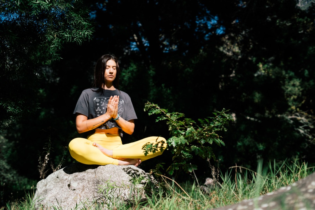 woman doing yoga on a rock