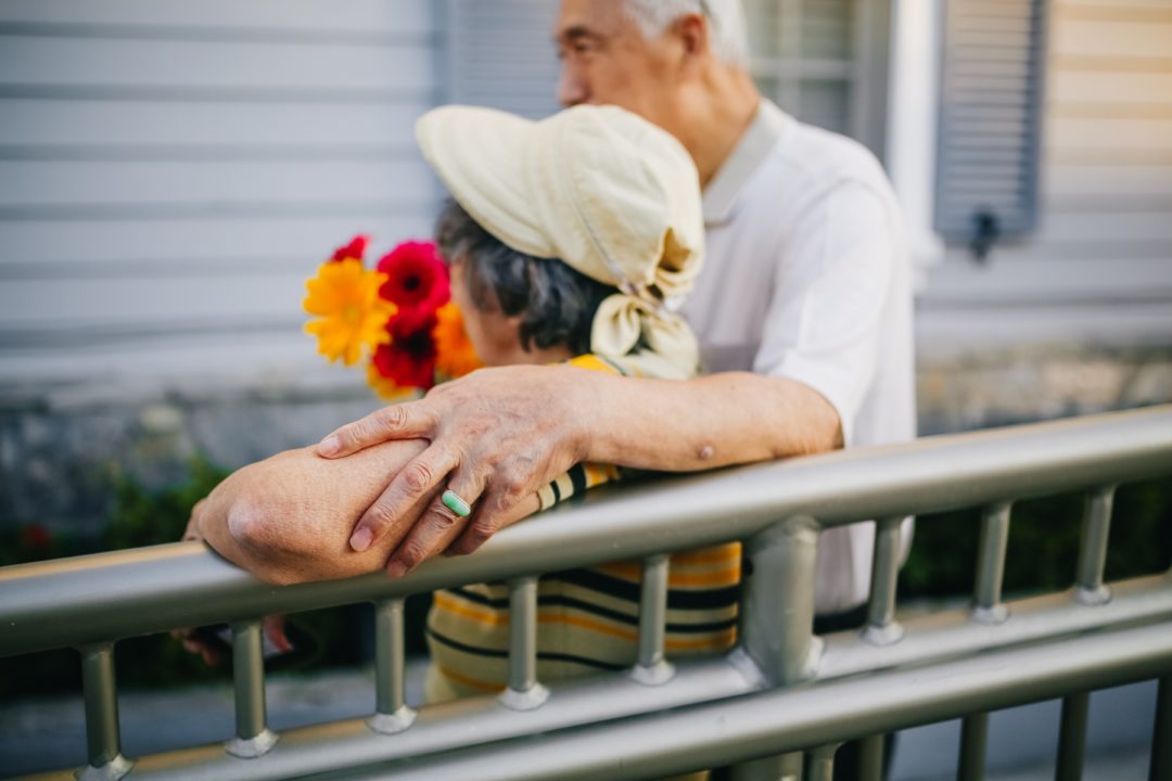 elderly couple hugging with flowers