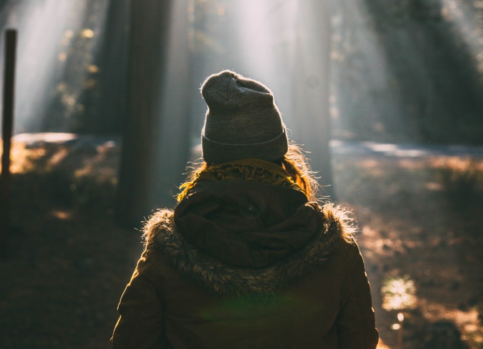 person in a sun beam in the forest