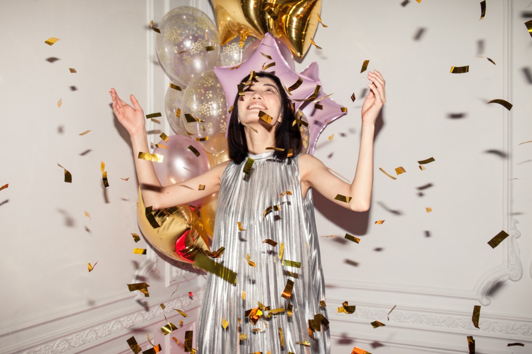 woman throwing confetti in celebration in front of balloons