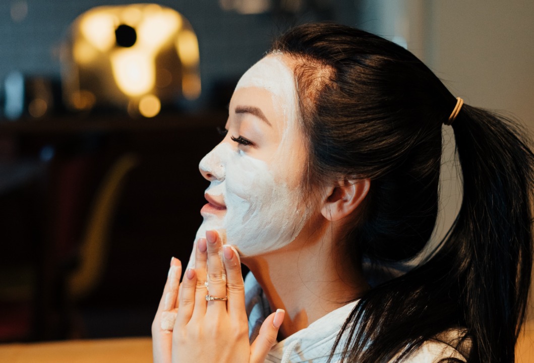 woman looking into mirror with face mask on 
