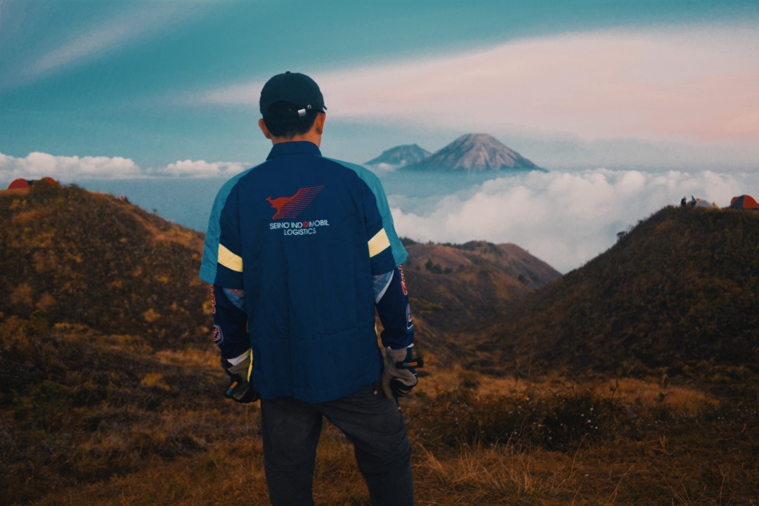 Man looking out at clouds and mountains