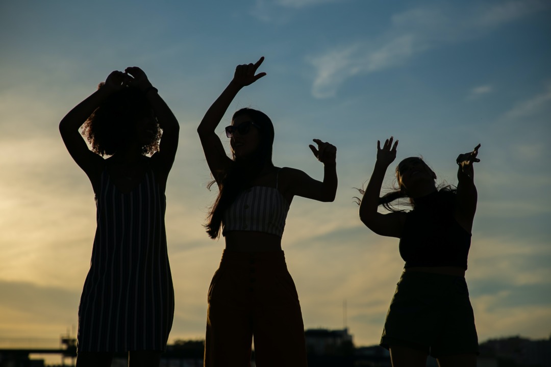 Three silhouettes dancing in the sunset
