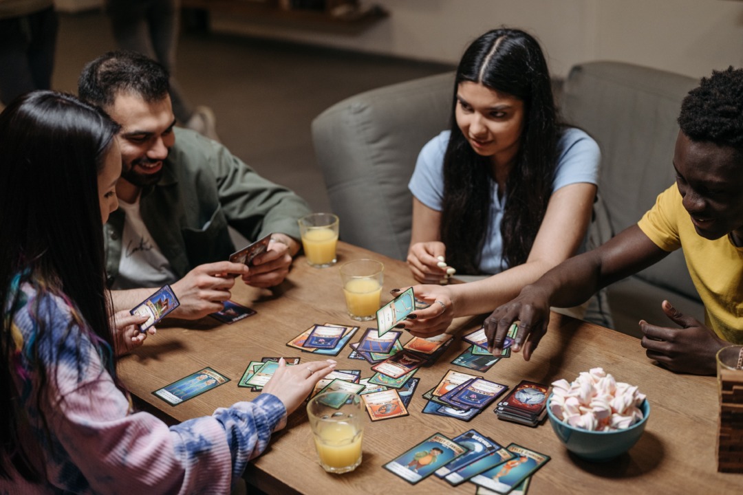 people playing a card game and drinking orange juice