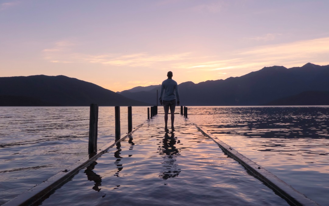 Man looking out at sunset from lake dock