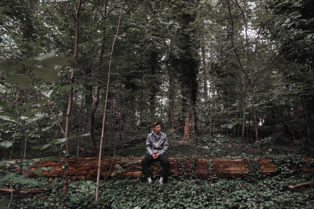 man sitting on fallen tree in the forest