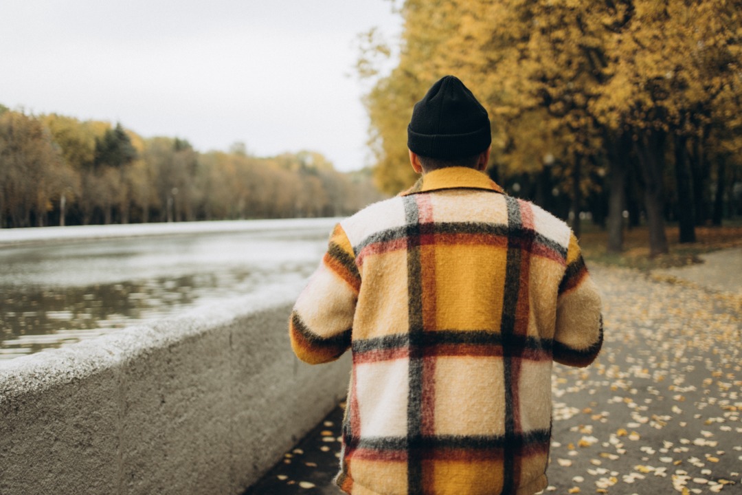 Person walking in a fall coat by a river