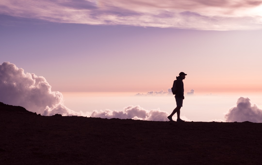 person walking at sunset with clouds