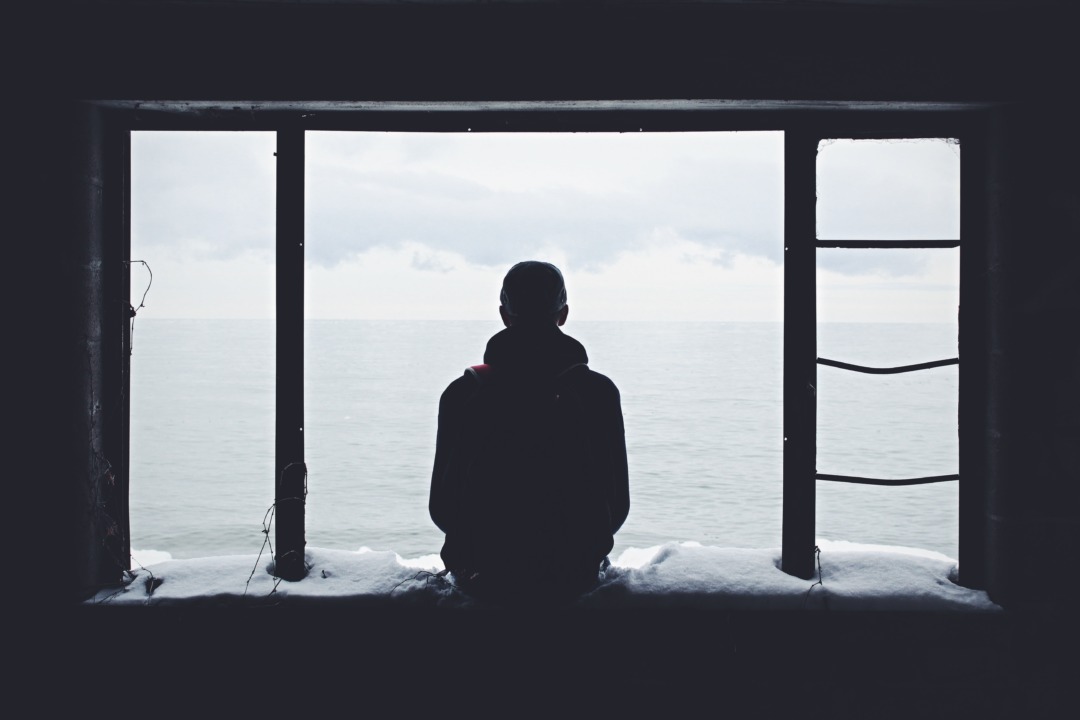 man looking out at cold day from window