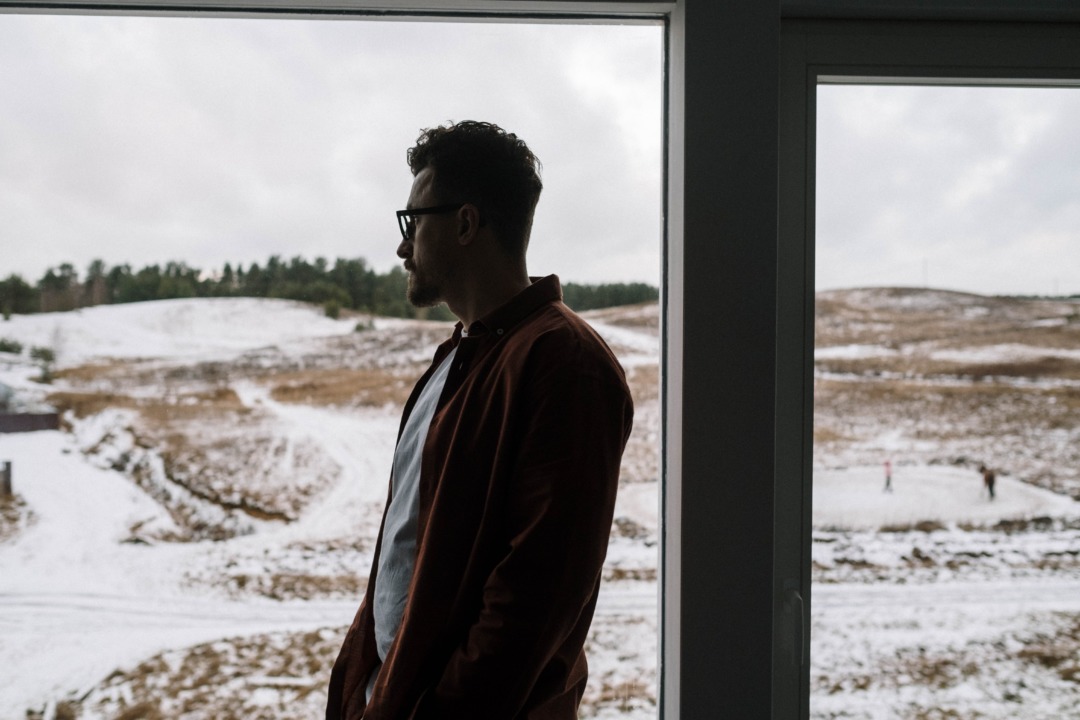 Man looking out window to snowy landscape