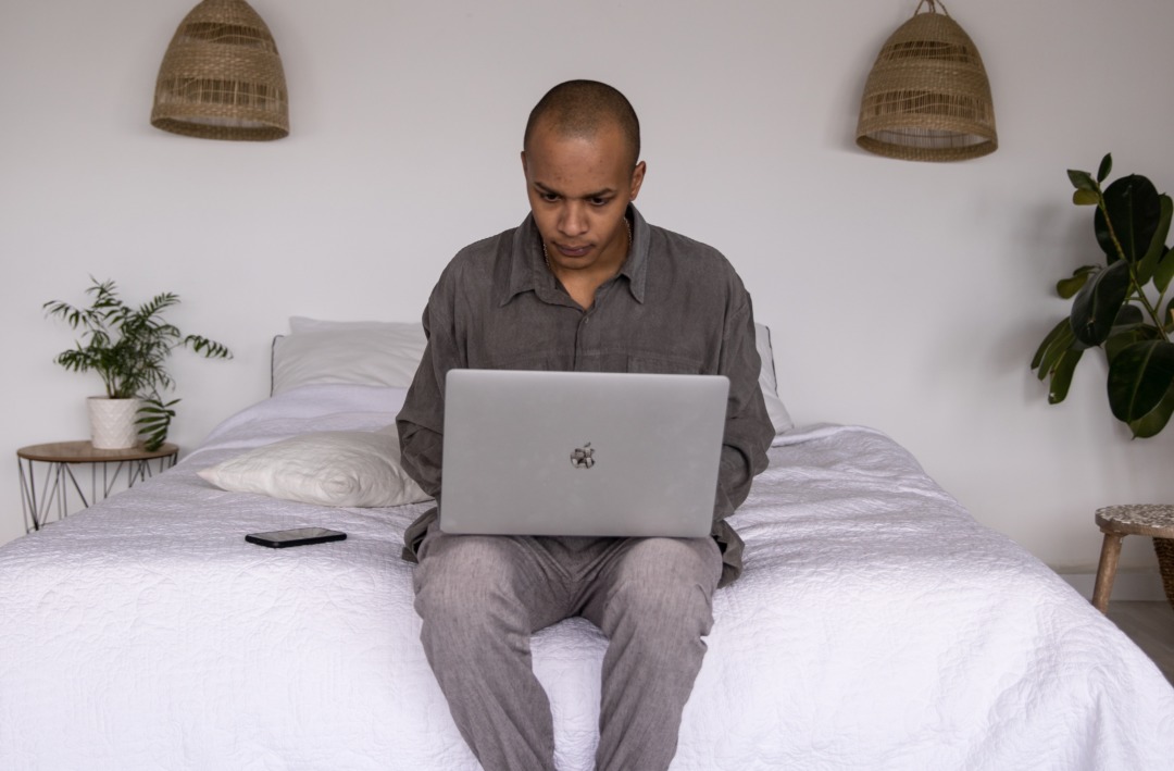 Man sitting on bed with a laptop