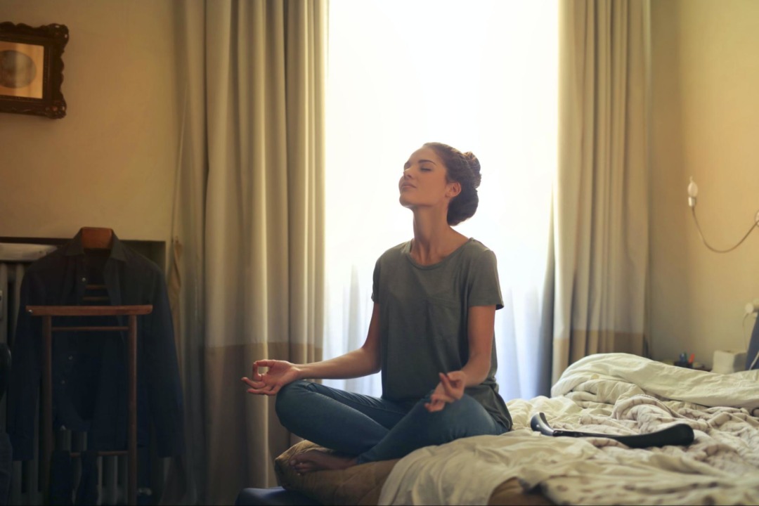 Woman sitting on bed and meditating