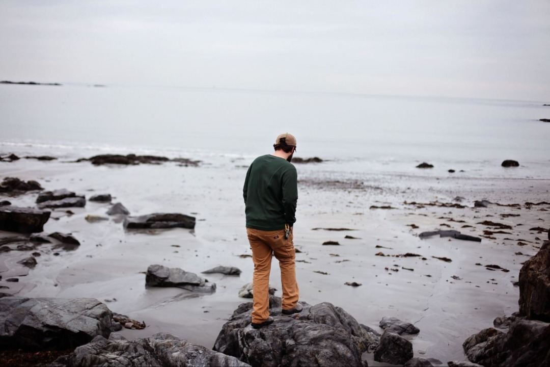 man looking at beach on cloudy day