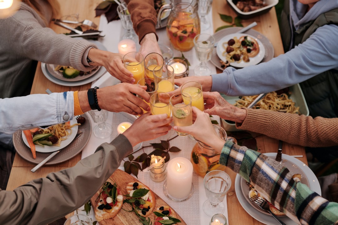 Friends toasting with alcohol-free juice drink over a dinner table