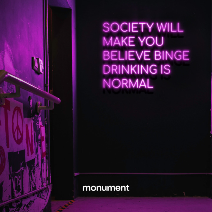 Neon sign that says "Society will make you believe binge drinking is normal"