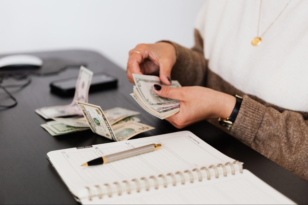 person counting money with a notebook