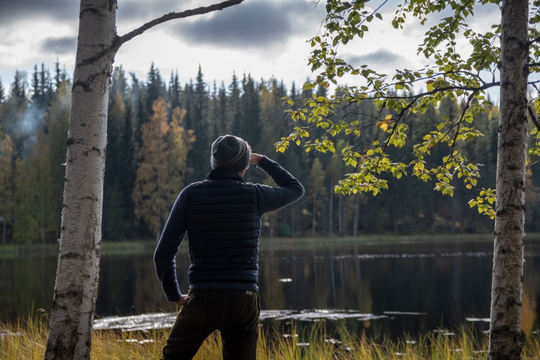 man looking at lake in fall time