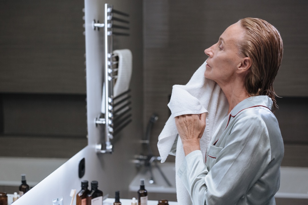 woman washing her face in the mirror