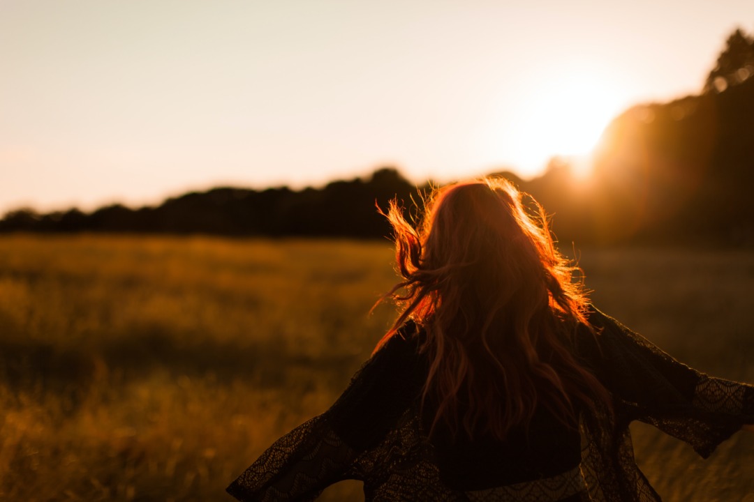 woman walking in field with wind blowing